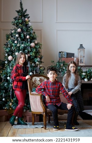 Three children a girl and a boy in festive attire are in a room decorated for the New year and Christmas. The concept of holidays and gifts.