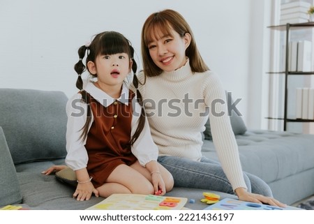 Mom and little 4 years old kid daughter playing education toy together at living room
