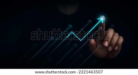Businessman's hand draws a rising arrow on dark background. Finger pointing on the shining arrowhead. Leadership, business growth and success concept. Increase business opportunities.
