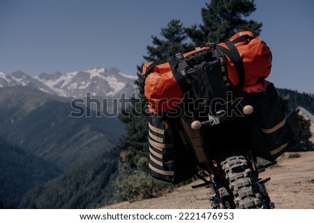 off-road motorcycle with dirt tires packed with dry bags and things for a long-distance motorcycle journey standing against the backdrop of a beautiful mountain landscape