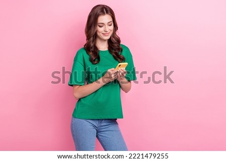 Photo of positive cheerful good mood girl with wavy hairdo dressed green t-shirt reading message isolated on pink color background