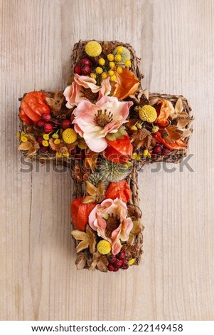 Cross made of artificial flowers and autumn plants. Decoration for All Saints Day (All Hallows)
