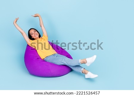 Photo of good mood nice girl bob hairdo wear yellow t-shirt lay stretching on purple bean bag chair isolated on blue color background