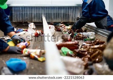 Worker sorts trash on conveyor belt at waste recycling plant Royalty-Free Stock Photo #2221528063