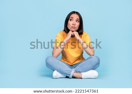 Full body photo of lovely young girl chinese sit floor sad psychotherapy dressed stylish yellow look isolated on blue color background
