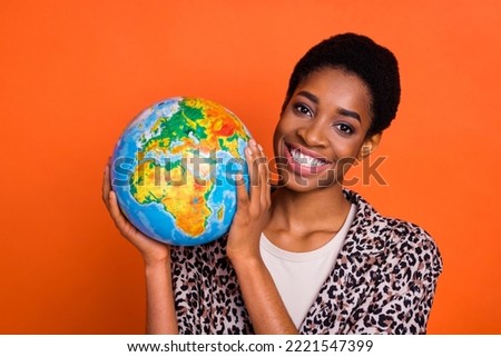 Photo of positive person hands hold globe toothy smile look camera isolated on orange color background