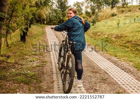 Young active girl in sportswear with a bicycle in a mountain area. Mountain biking, woman with fat bike enjoys summer vacation. Close up