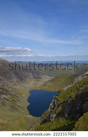 a view looing down in the crater of Cadair Idris with a mountain view behind it	