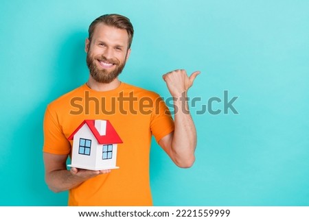 Photo of cool beard guy hold house index promo wear orange t-shirt isolated on teal color backgroiund