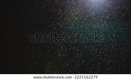 Natural dust particles floating on black background with light. Glittering sparkling particles in the air with effect bokeh. Macro shot of texture whites snow, smoke, steam, fog with glare luminosity. Royalty-Free Stock Photo #2221562379