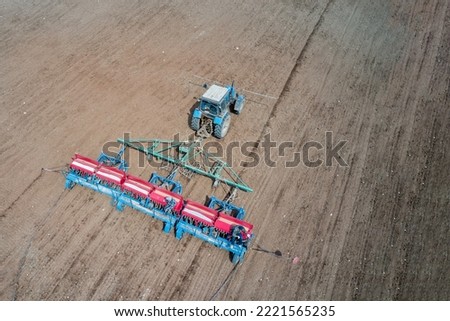 Seeding. Sowing of grain crops with simultaneous application of complex fertilizers. A tractor with a seeder is working in the field. There are two workers on the seeder. Shooting from a drone.
