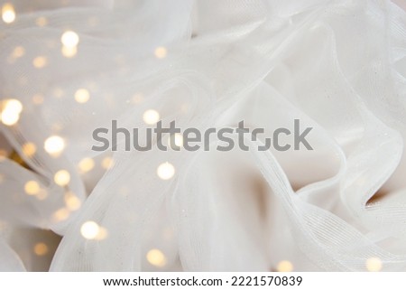 White tulle fabric background with bokeh overlay. Glitter chiffon texture, wedding concept. Close up.