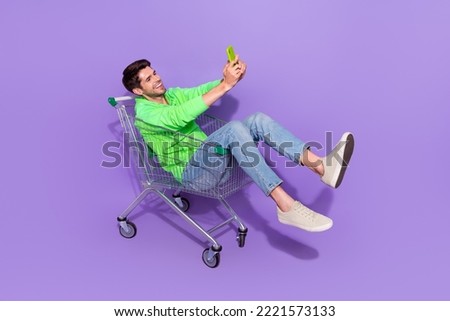 Full length photo of funky pretty man wear green hoodie supermarket tray rider tacking selfie modern device isolated purple color background
