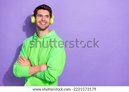 Photo of glad interested guy with brunet hairdo dressed green hoodie headphones look empty space isolated on purple color background Royalty-Free Stock Photo #2221573179