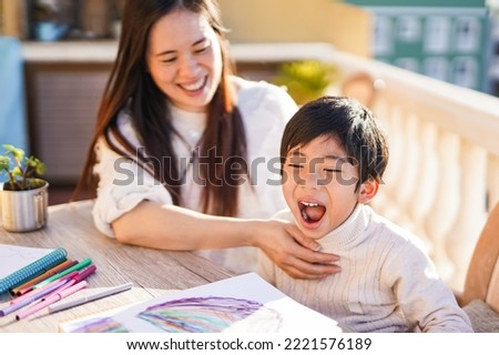 Asian mother and child having playful time together at home patio - Focus on little boy screaming
