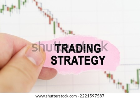 Business and trading concept. Against the background of the quote chart, a man holds a sign with the inscription - Trading strategy