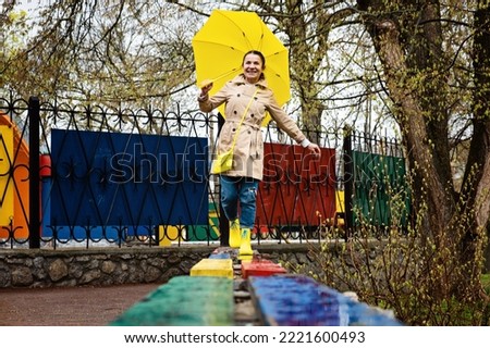 Autumn depression and how to deal with it. Seasonal affective disorder SAD. Happy senor woman in yellow rain boots and umbrella having fun and enjoy life in rainy autumn park Royalty-Free Stock Photo #2221600493