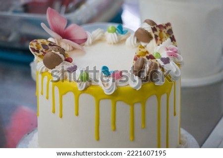 Colorful decorated cake for kids birthday party. Birthday cake with fancy decoration. Nicely decorated cake with colorful toppings. Kids-friendly decoration. Whipped cream, macarones and candy. 