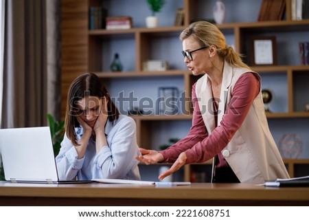 Angry female boss scolding scared office worker. Demanding manager leader is annoyed at laziness and mistakes in work of employee. Authoritarian leadership, abuse of power, malfeasance in office Royalty-Free Stock Photo #2221608751