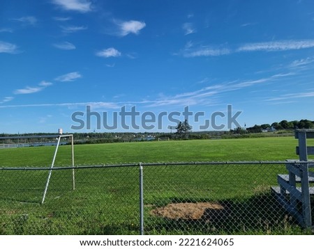 A large mowed sports field under a blue summer sky.