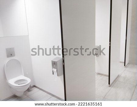 Clean white Public Washroom WC stall with white plastic toilet bowl seat inside with open lid Royalty-Free Stock Photo #2221635161