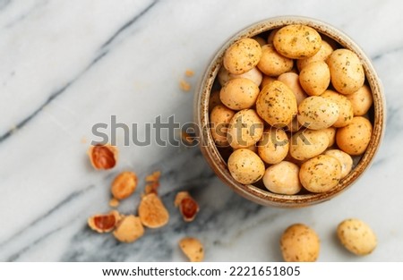 Crispy   Nuts. Peanuts in glaze with seasonings and spices. A delicious snack for beer. Marble background. Selective focus, top view, copy space