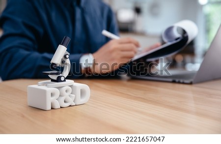 R and D and microscope on table in front of working businessman, research and development and strategy of work improvement concept. Royalty-Free Stock Photo #2221657047