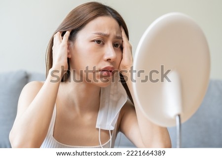 Expression worry asian young woman hand touching pustule around the chin and mouth, allergic when wear mask, makeup, show squeezing pimple spot from face. Beauty care, skin problem by acne treatment. Royalty-Free Stock Photo #2221664389
