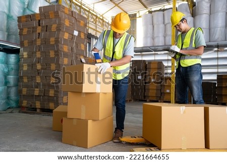 Warehouse workers work in teams and lift sealed cardboard boxes for shipments in large warehouses.