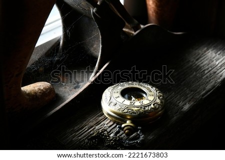 An old vintage pocket watch resting on a window ledge with dramatic lighting. 