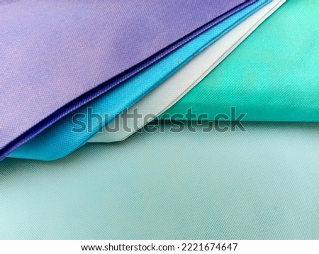Bandung, Nov 2, 2022 : Curve line pattern from colorful part of nylon side bags that arranged on light blue fabric bags as background.