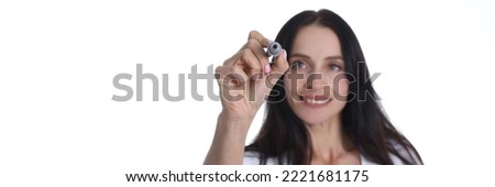 Portrait of smiling woman holding marker and writing something in air. Young cheerful female drawing something on virtual screen. People lifestyle concept