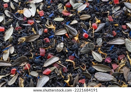 Black herbal tea with lingonberry leaf, rowan berries, calendula and cornflower petals. Close up herbal tea
