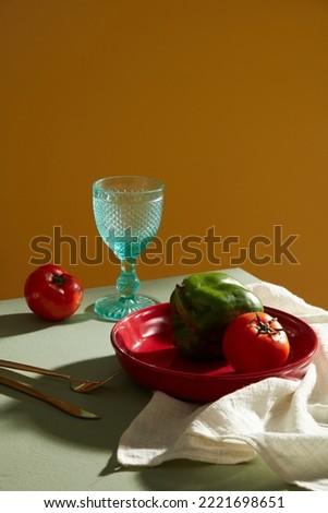 Still life of fresh vegetable on the red plates. Glass, knife, fork and napkin  display the flatlay. Tableware setting. Art decoration
