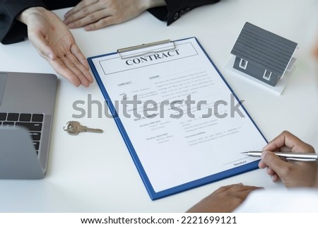 A businesswoman signing a new home purchase or sale from a real estate agent provides tax advice and details of the deal discussed.