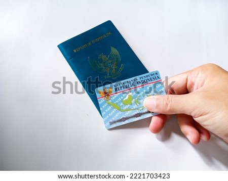 Republic of Indonesia green passport and Indonesia Identity card in human hand on a white background.