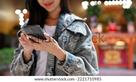 Close up view of your woman holding smartphone during her vacation with Asian tradition temple background 