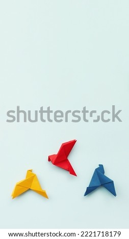 three paper origami pigeons red, blue, yellow on light background, background, vertical, 16:9, copy space