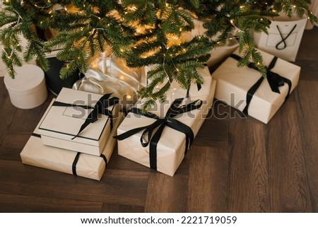 Stylish Christmas gifts lie under the Christmas tree with lights, top view Royalty-Free Stock Photo #2221719059