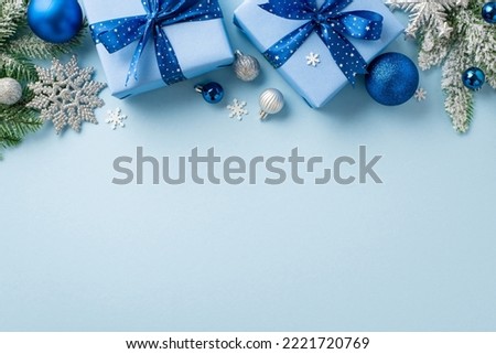 Christmas Eve concept. Top view photo of gift boxes with bows blue and silver baubles snowflake ornaments pine branches in snow and confetti on isolated pastel blue background with empty space