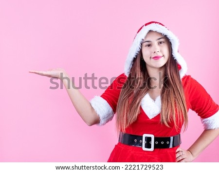 closeup of caucasian happy woman wearing santa clothes on pink solid background laughing and pointing finger