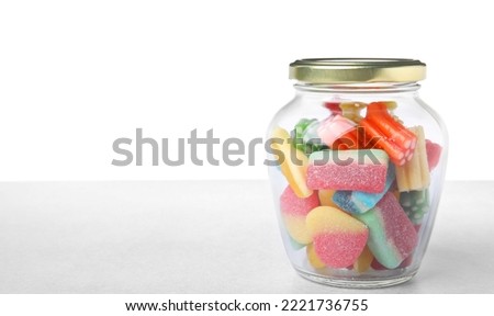 Tasty jelly candies in jar on light grey table