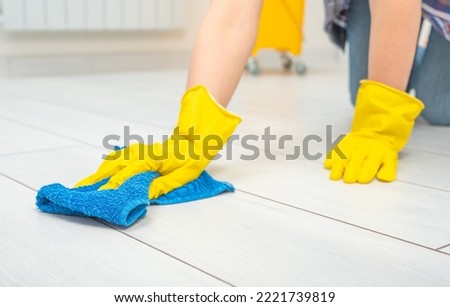 Deep Cleaning service. Professional cleaner washing white floor in living room of apartment. female hands in gloves wipe white floor with text cleaning. Cleaning service concept Royalty-Free Stock Photo #2221739819