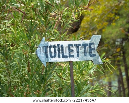 Sign in a park with the inscription toilets. A sign with an arrow pointing to the left.