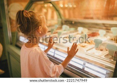 Cute little girl standing near ice-cream shop, choosing ice-cream. Royalty-Free Stock Photo #2221747949