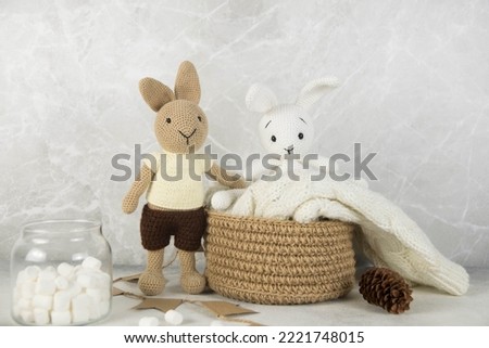Christmas home decoration. Two Knitting toys rabbits are on knitting basket with marchmelloy in gray background.