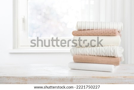 Pile of warm clothes on wooden table with copy space