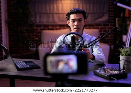 Asian vlogger broadcasting product review with headset on social media channel, recording online vlog and talking about audio headphones. Filming recommendation video with livestreaming station.