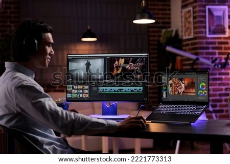 Young videographer working on video production, editing multimedia montage and movie footage to create agency content. Using software on computer to edit professional film with color grading effects. Royalty-Free Stock Photo #2221773313