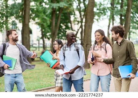 group of happy students walking through the park. Royalty-Free Stock Photo #2221774237